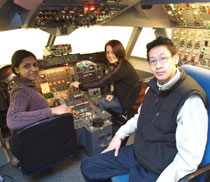 Photo of aircraft engineering students Aneja Mullenkuzhyil Jose, left, Lauren Clark and Peter Mok testing out the new Boeing 747 fixed-based simulator. 